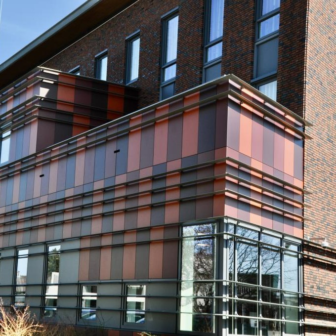 a facade of a building with HPL planks in dark red and brown colours